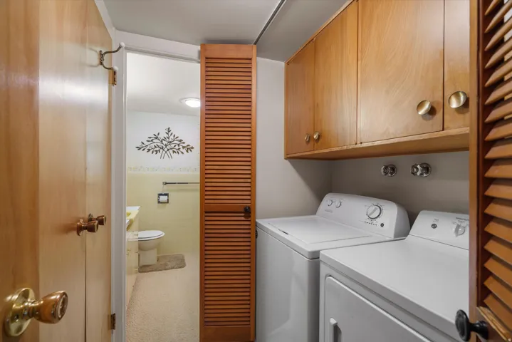 Dedicated laundry area featuring upper wood cabinetry and a side-by-side washer and dryer