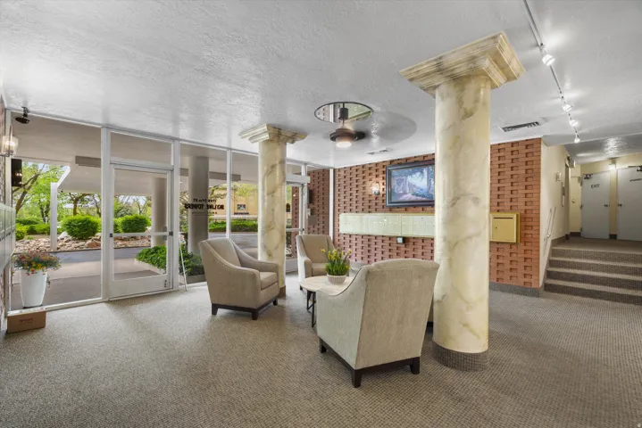 Building entry featuring a glass door, floor-to-ceiling windows, and two marble-look columns