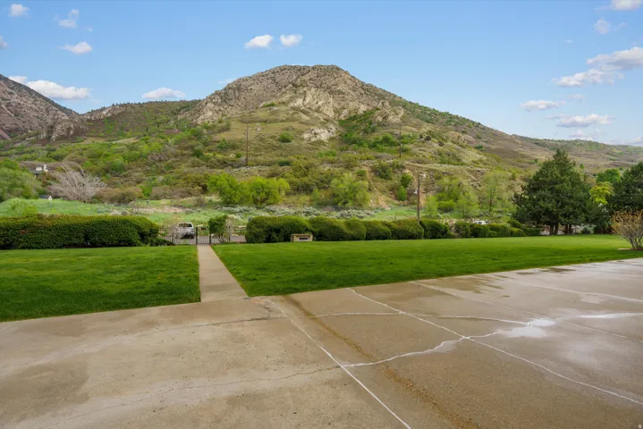 Expansive concrete driveway and walkway leading to a manicured lawn