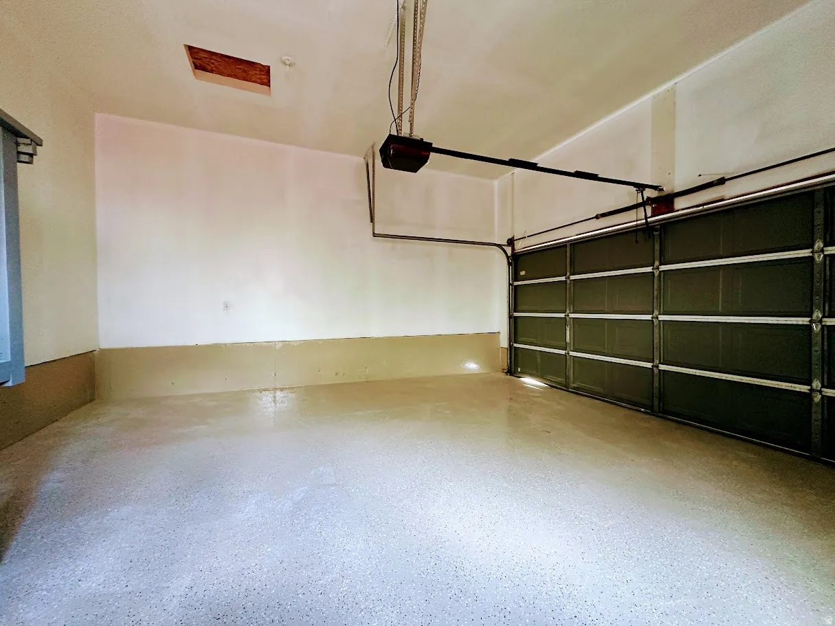Spacious garage featuring a durable speckled epoxy floor, painted walls, and an automatic garage door opener