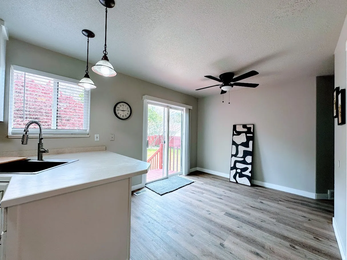 Kitchen and dining area featuring wood-finish flooring, a ceiling fan, pendant lighting, and light-toned countertops