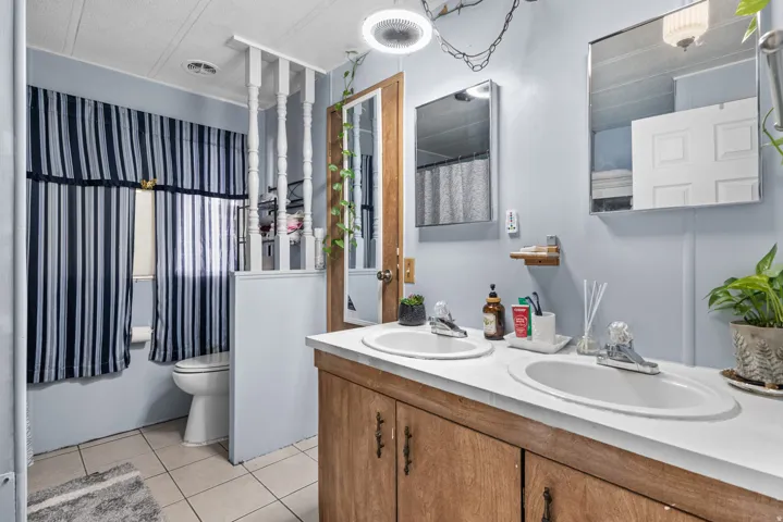Bathroom featuring a dual sink vanity with white countertops, wood-finish cabinetry, and individual mirrors