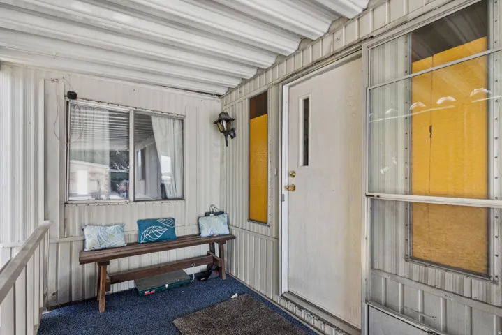 Covered porch entry featuring a white door, a wall-mounted light fixture, and horizontal siding