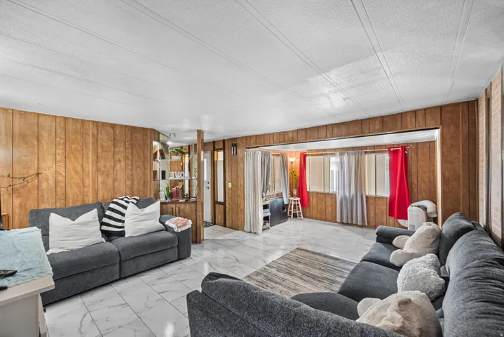 Living area featuring wood paneling and white tile flooring