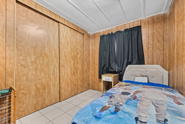 Wood-paneled walls featuring integrated sliding closet doors, white ceiling panels, and tile flooring