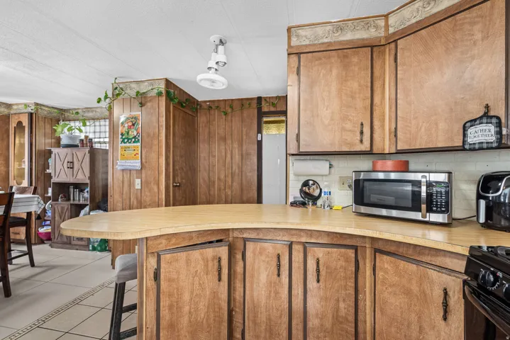 Kitchen featuring wood-paneled walls, wood-finish cabinetry with decorative hardware, and a curved countertop