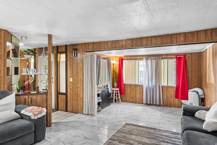 Spacious interior featuring wood-panel walls, patterned tile flooring, and multiple windows