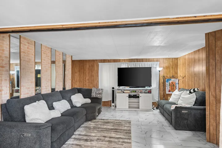 Living area featuring white tile flooring and wood paneling on walls