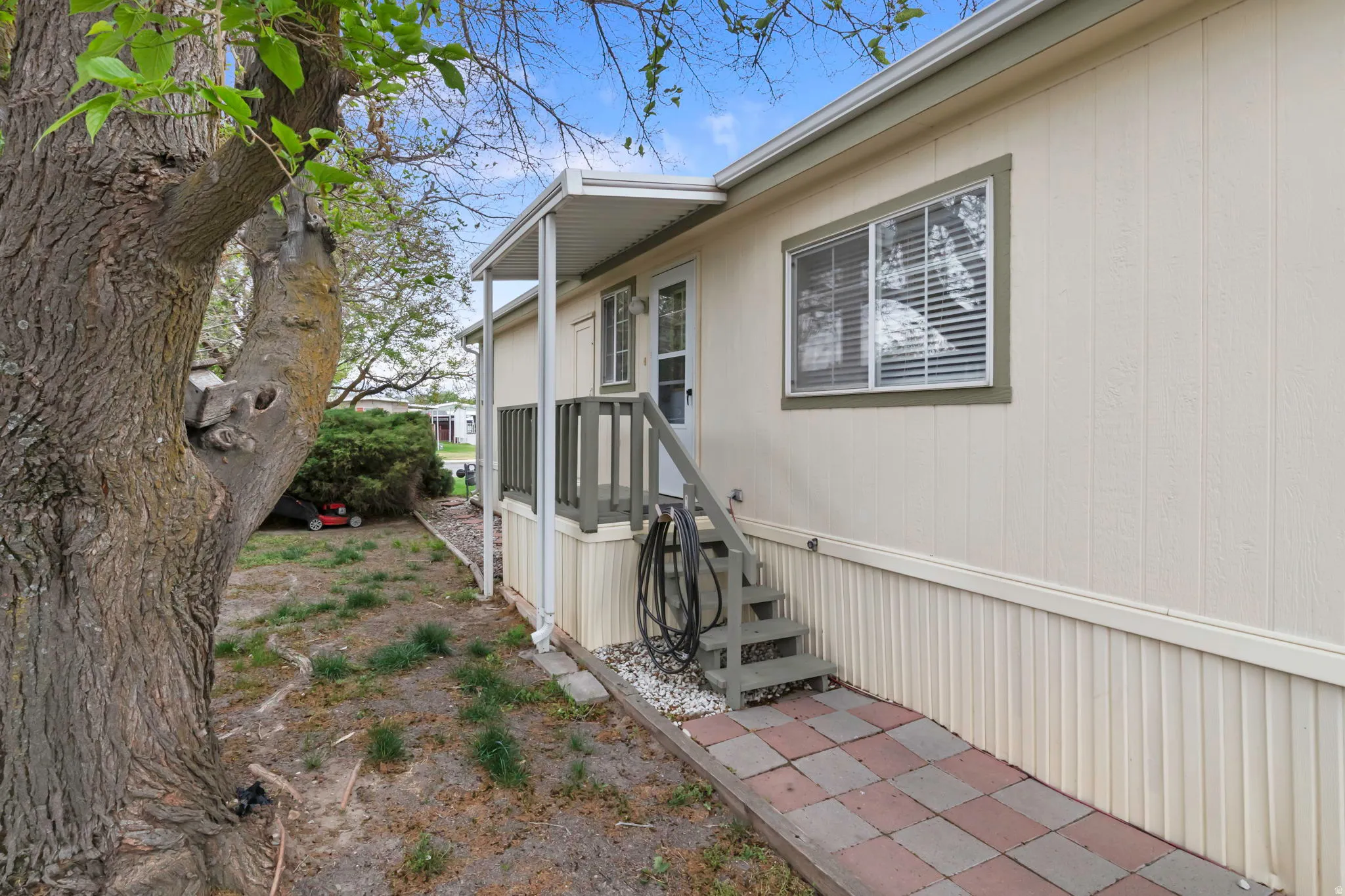 Exterior featuring light-colored vertical siding, contrasting trim, a covered entry, and a paver pathway