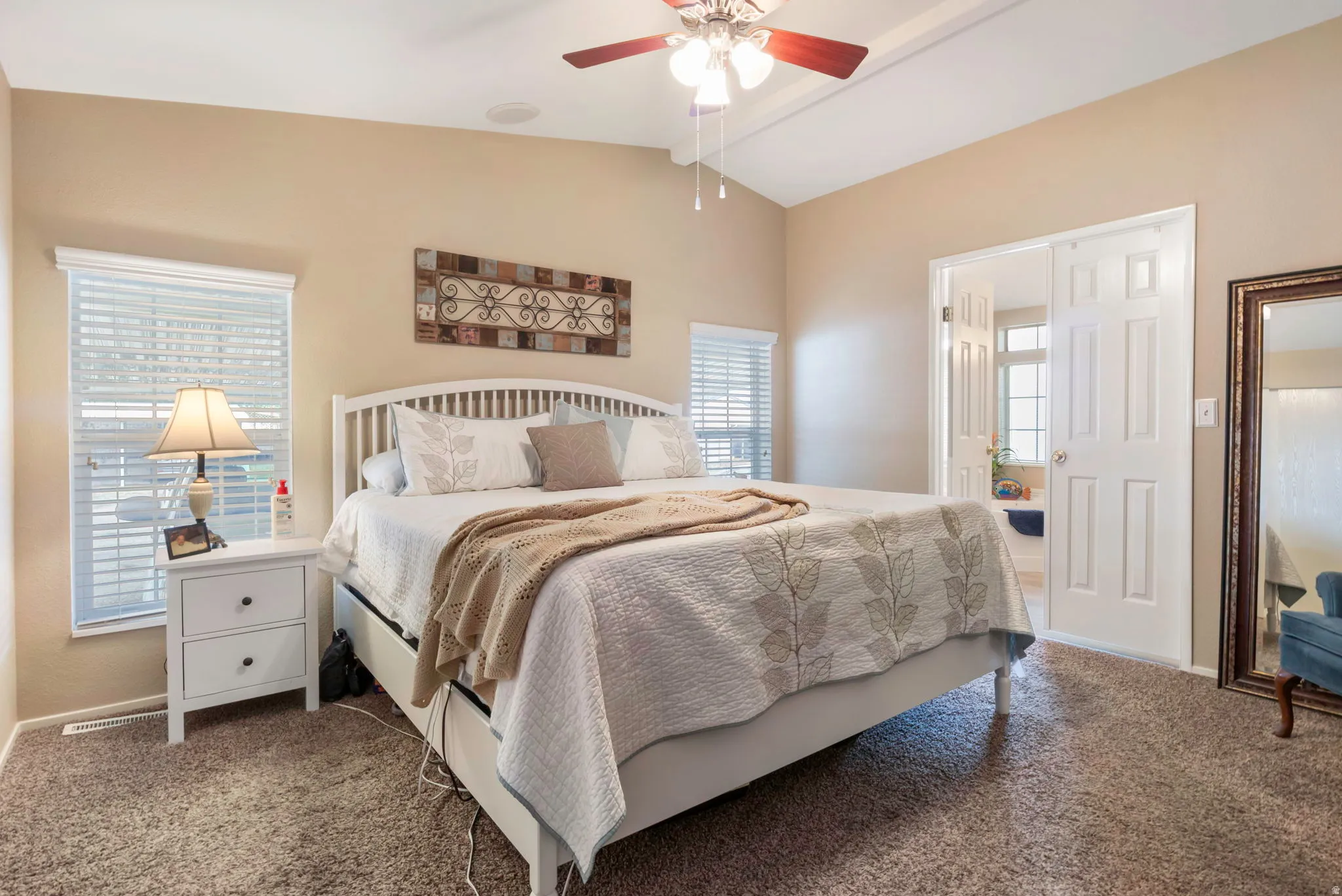 Spacious bedroom featuring vaulted ceilings, carpet flooring, and a ceiling fan with integrated lighting
