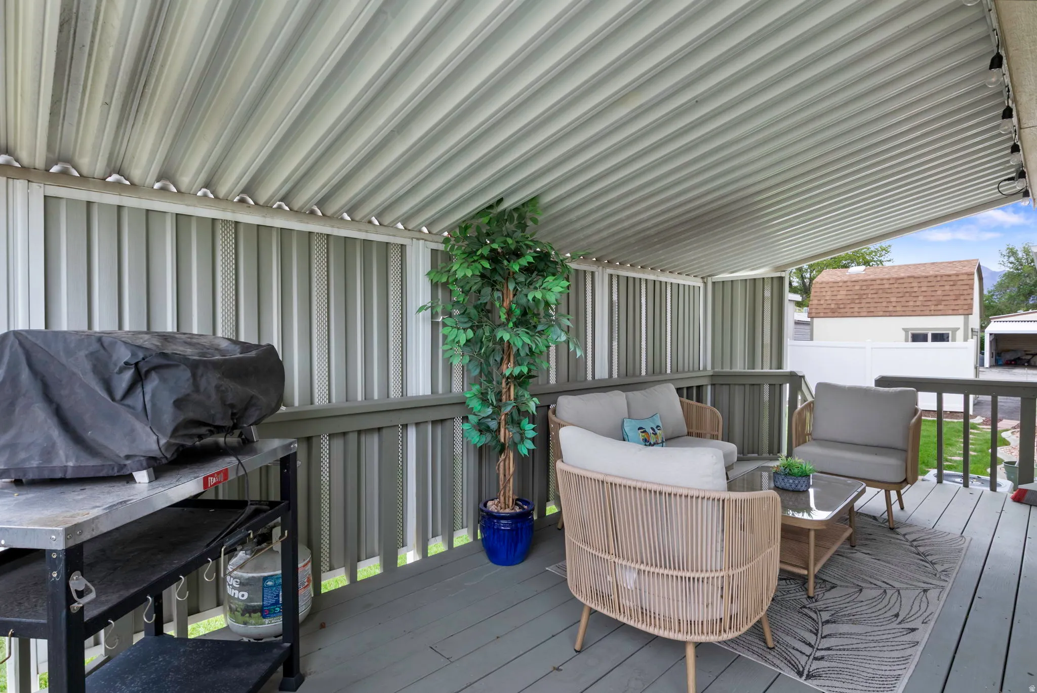Covered patio featuring a corrugated metal ceiling and string lighting