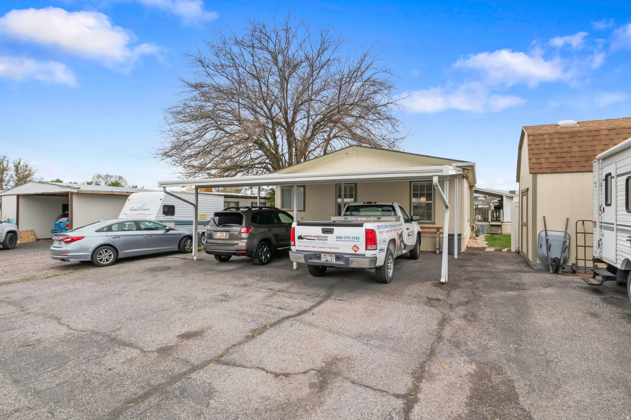Property exterior featuring a carport, an additional shed with a shingle roof, and a gravel parking area