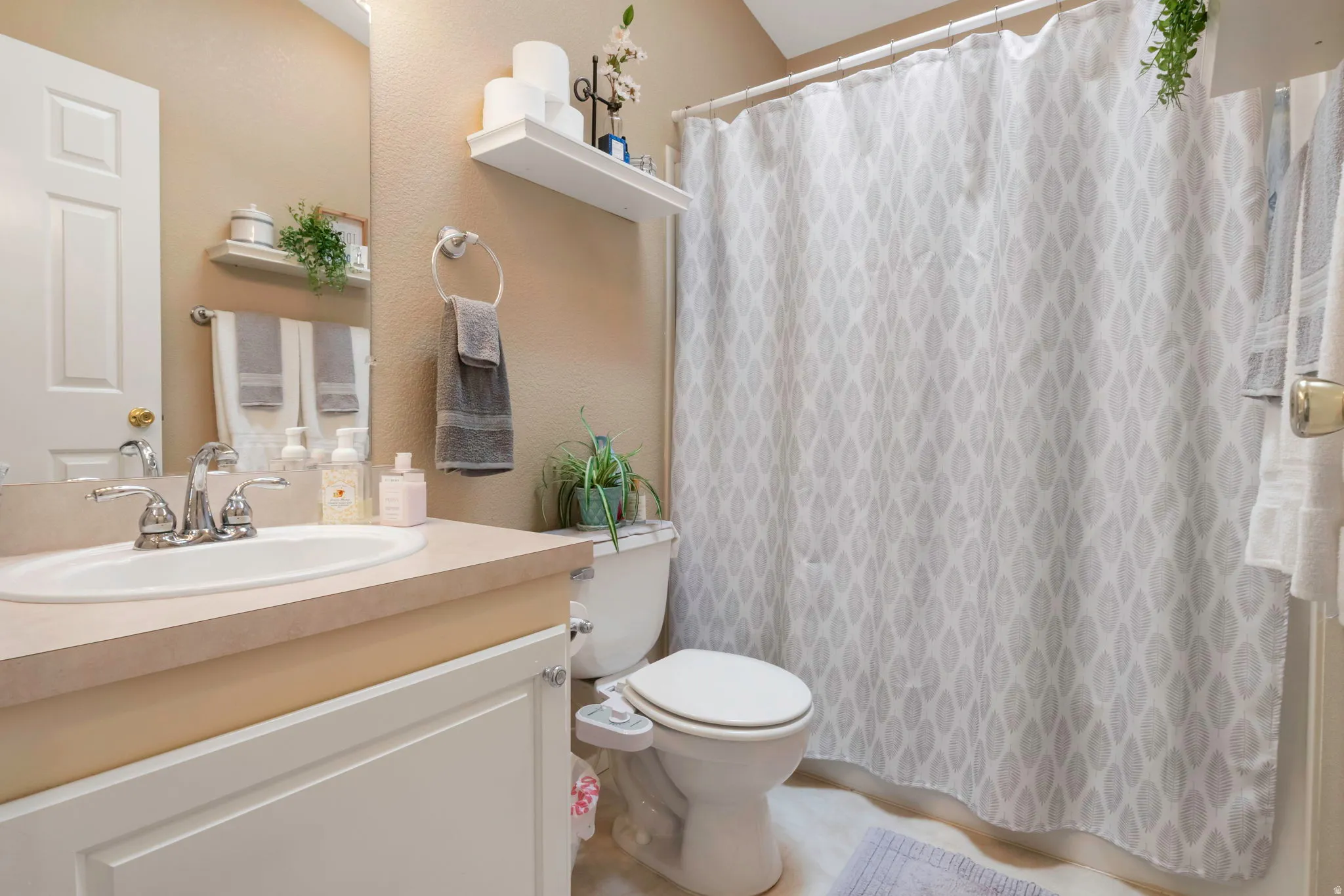 Bathroom featuring a vanity with an integrated sink, a light-colored countertop, white cabinetry, a chrome-finish faucet, and a wall-mounted mirror
