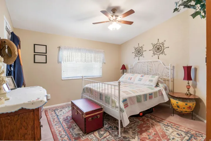 Bedroom featuring a vaulted ceiling, ceiling fan with integrated lighting, window with blinds, and neutral wall tones