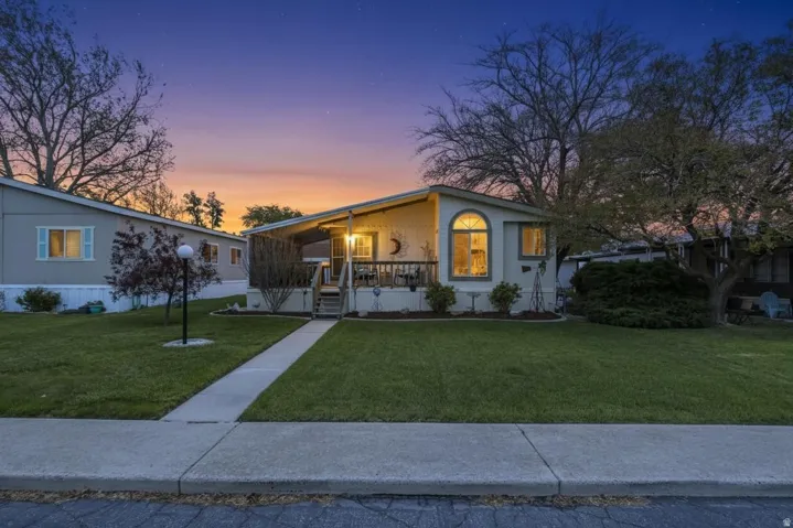 Cream-colored exterior featuring a covered porch with railings, an arched window, and a concrete pathway