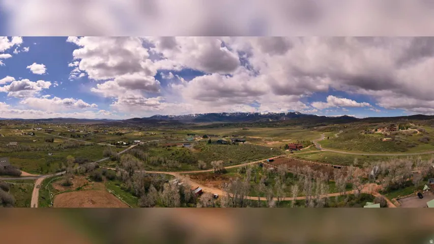 Expansive rural landscape featuring distant snow-capped mountains and scattered residential structures