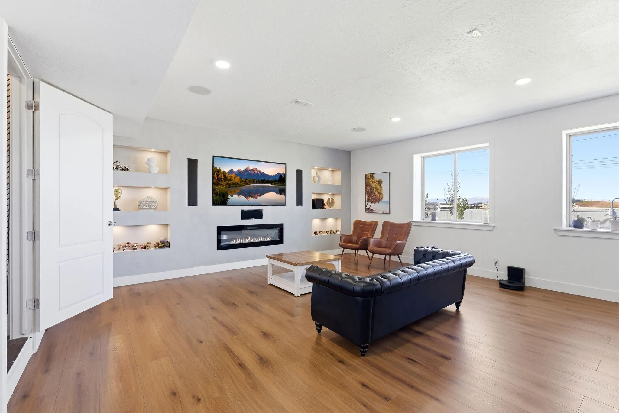 Living room featuring built in features, a glass covered fireplace, light wood-type flooring, and recessed lighting