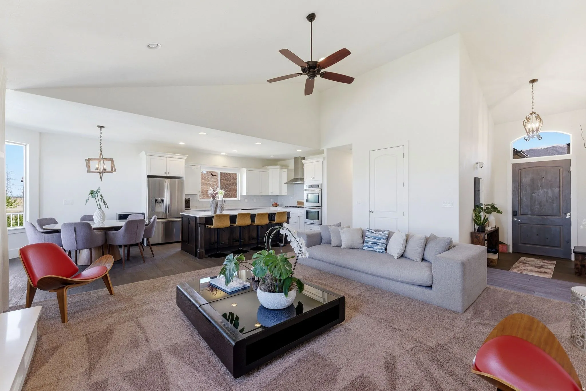 Living area featuring hanging lights, light wood-type flooring, a ceiling fan, and lofted ceiling