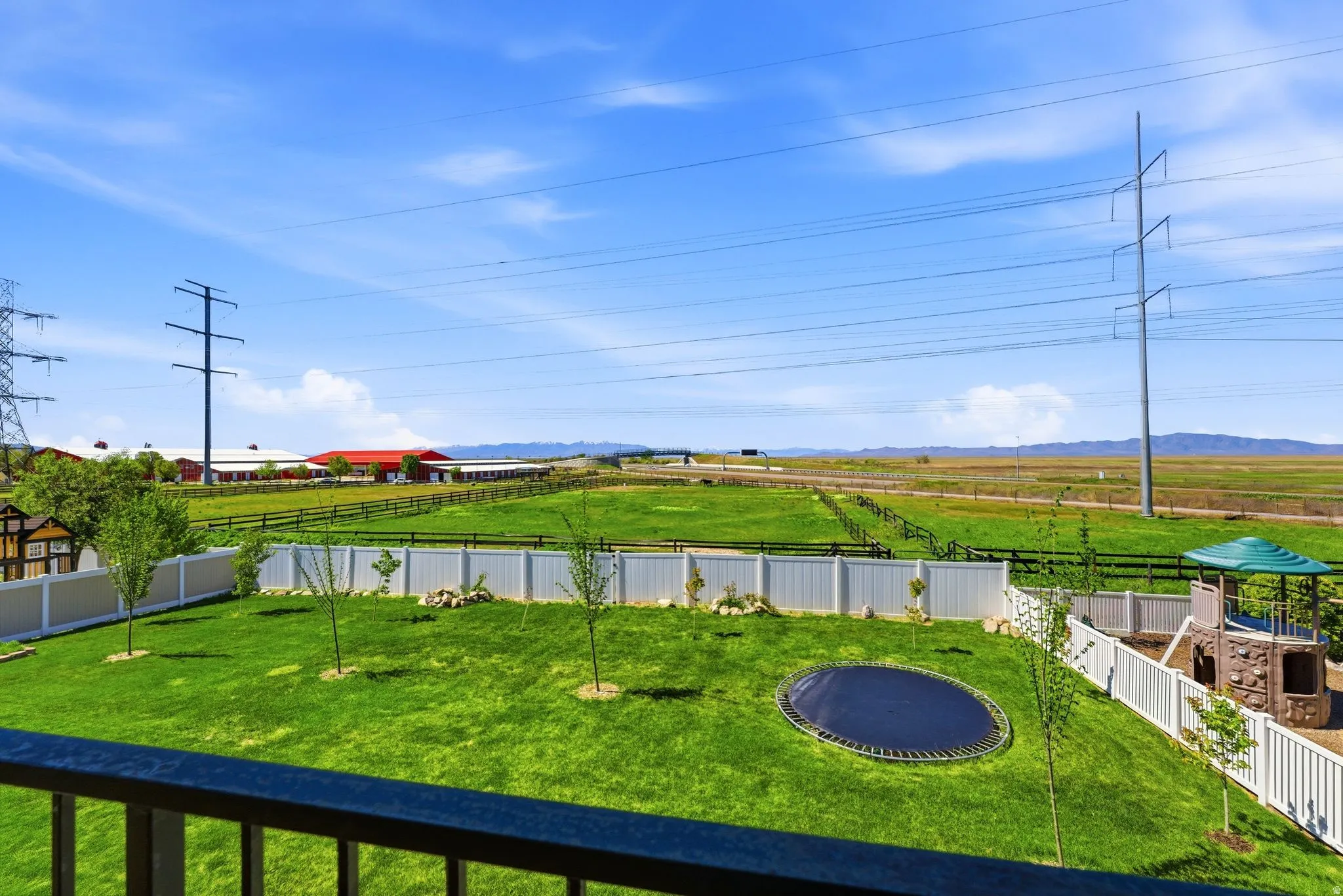 Fenced backyard featuring a view of countryside, a trampoline, and a mountain view