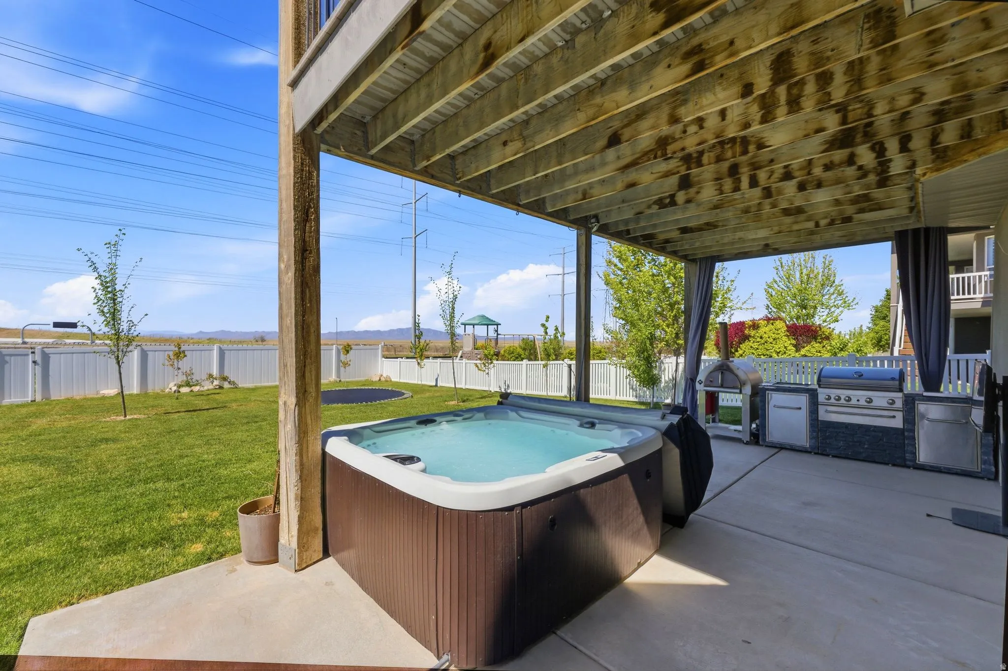 Fenced backyard with a hot tub, a patio area, and area for grilling