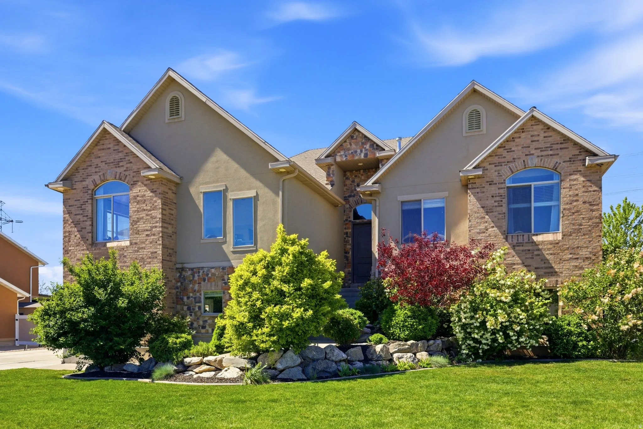 Traditional home with stucco siding, a front lawn, stone siding, and brick siding