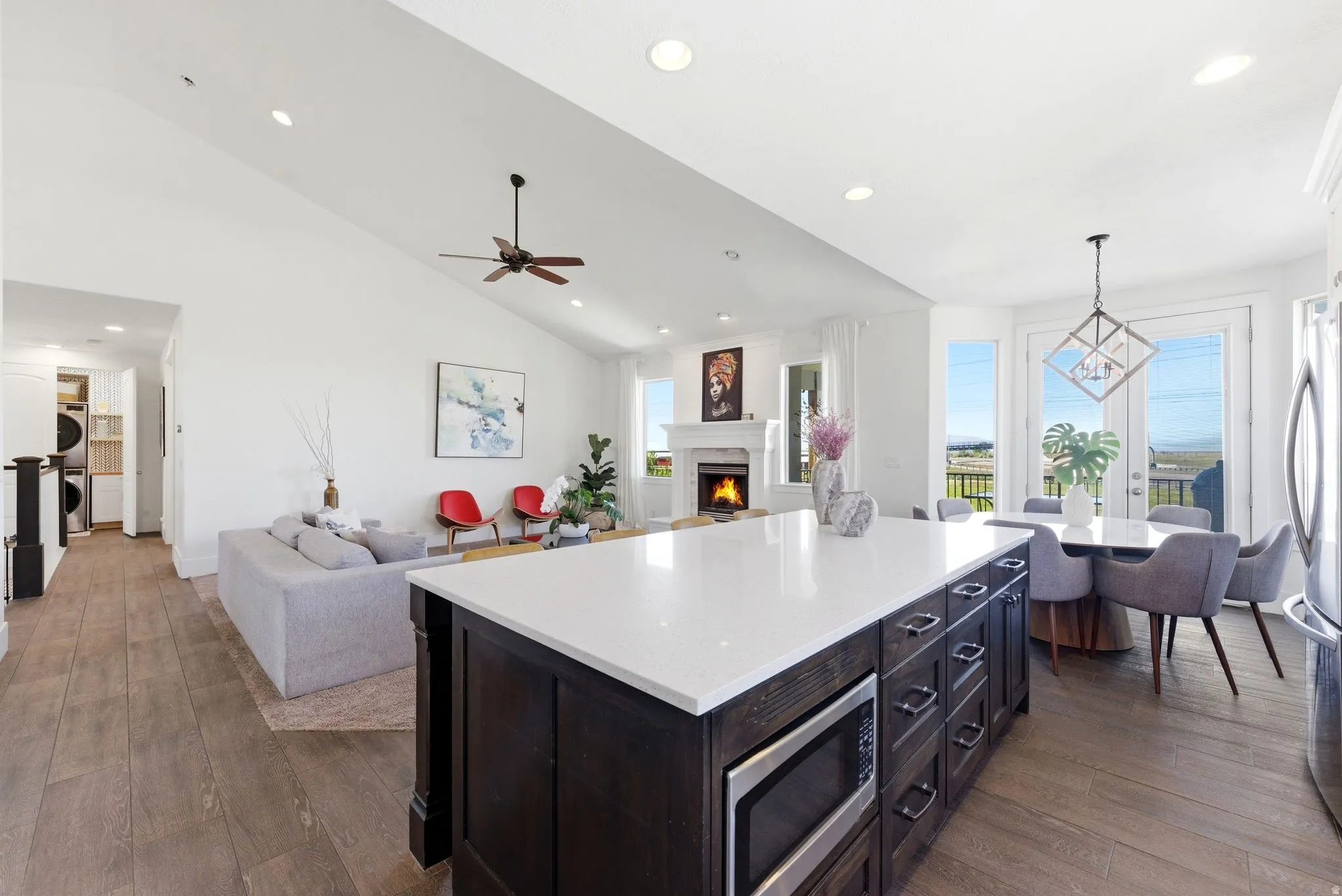 Kitchen featuring open floor plan, dark wood finished floors, a kitchen island, stainless steel appliances, and lofted ceiling