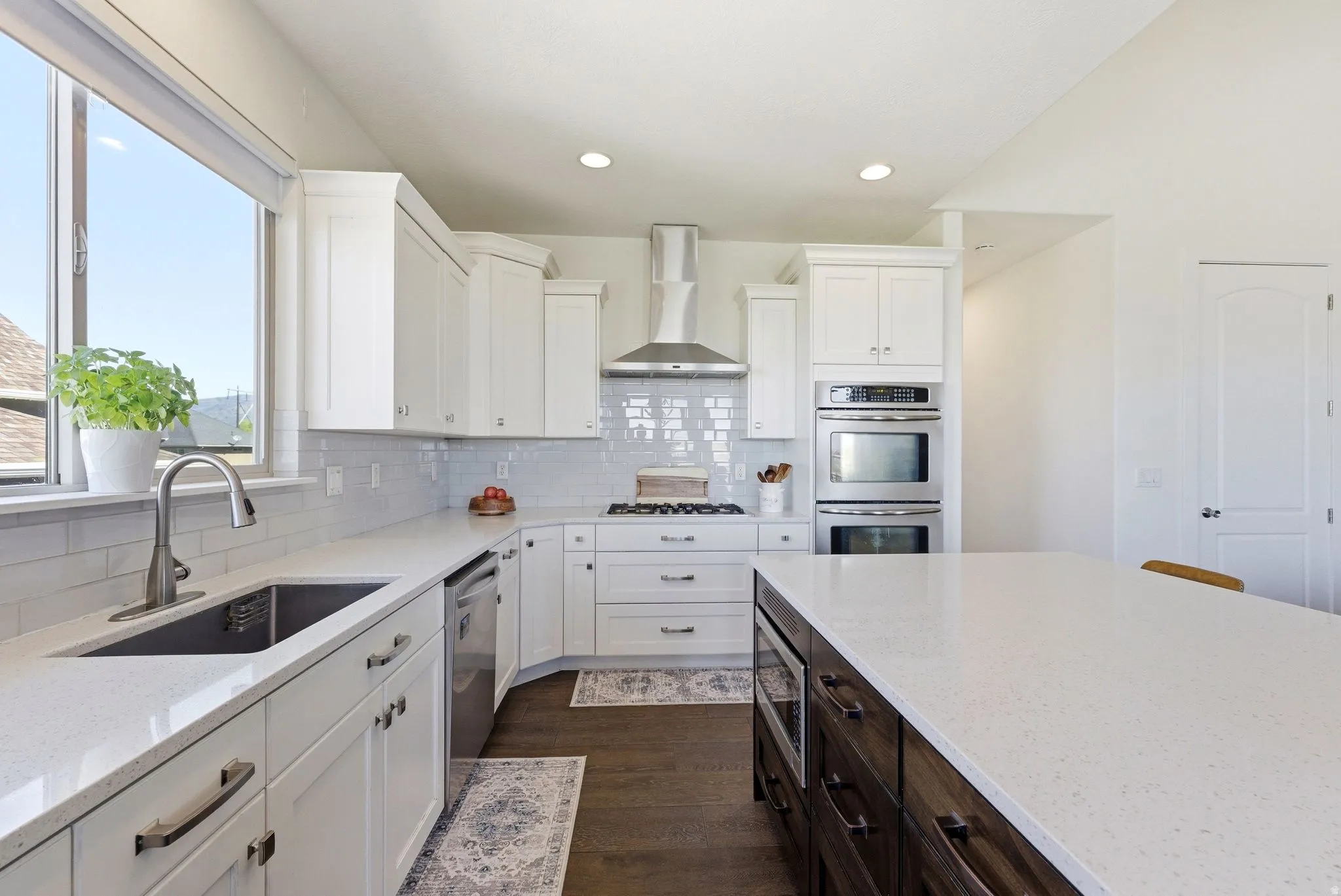 Kitchen with dark wood finished floors, light stone countertops, stainless steel appliances, decorative backsplash, and recessed lighting