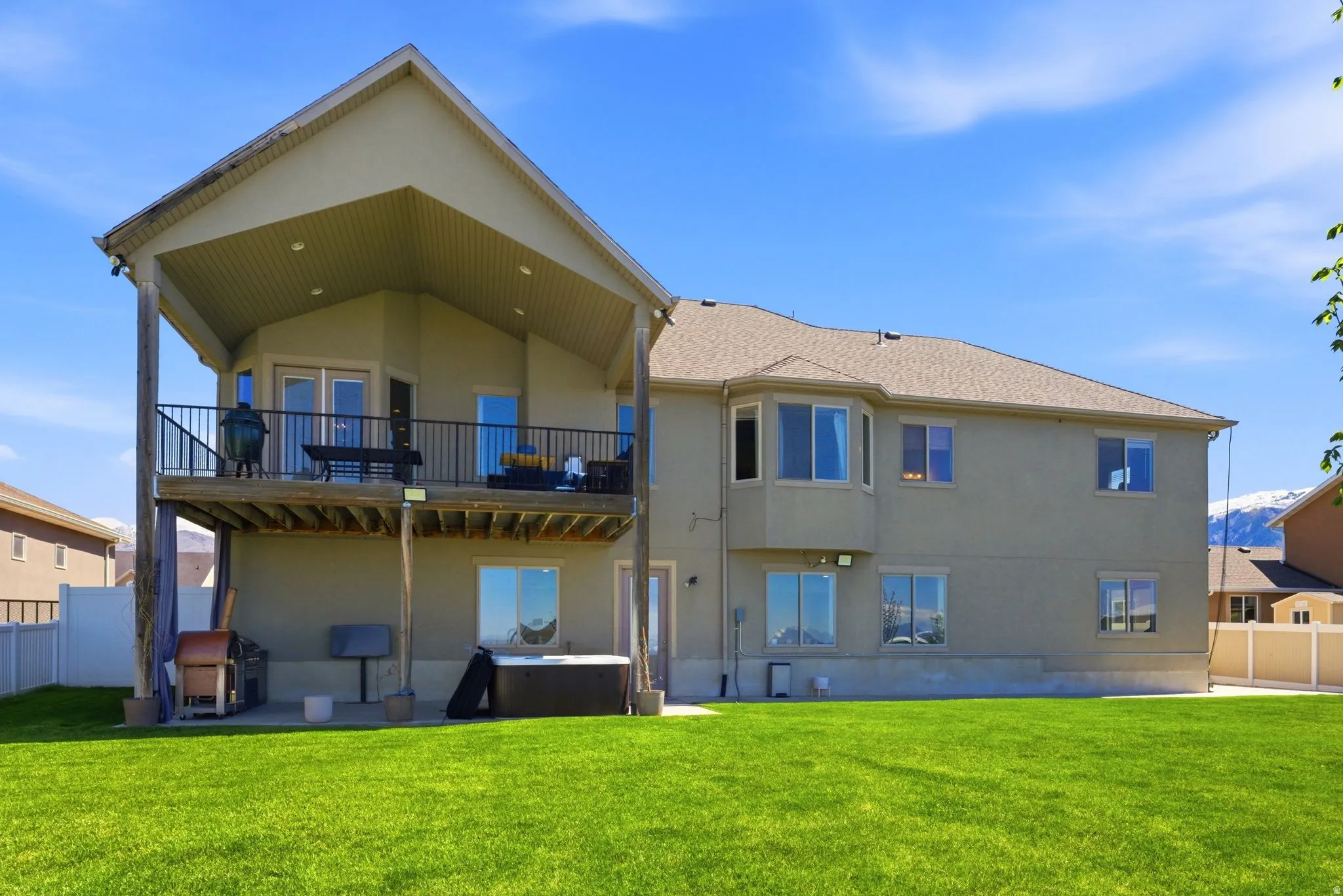 Rear view of property with stucco siding, a patio area, and a hot tub
