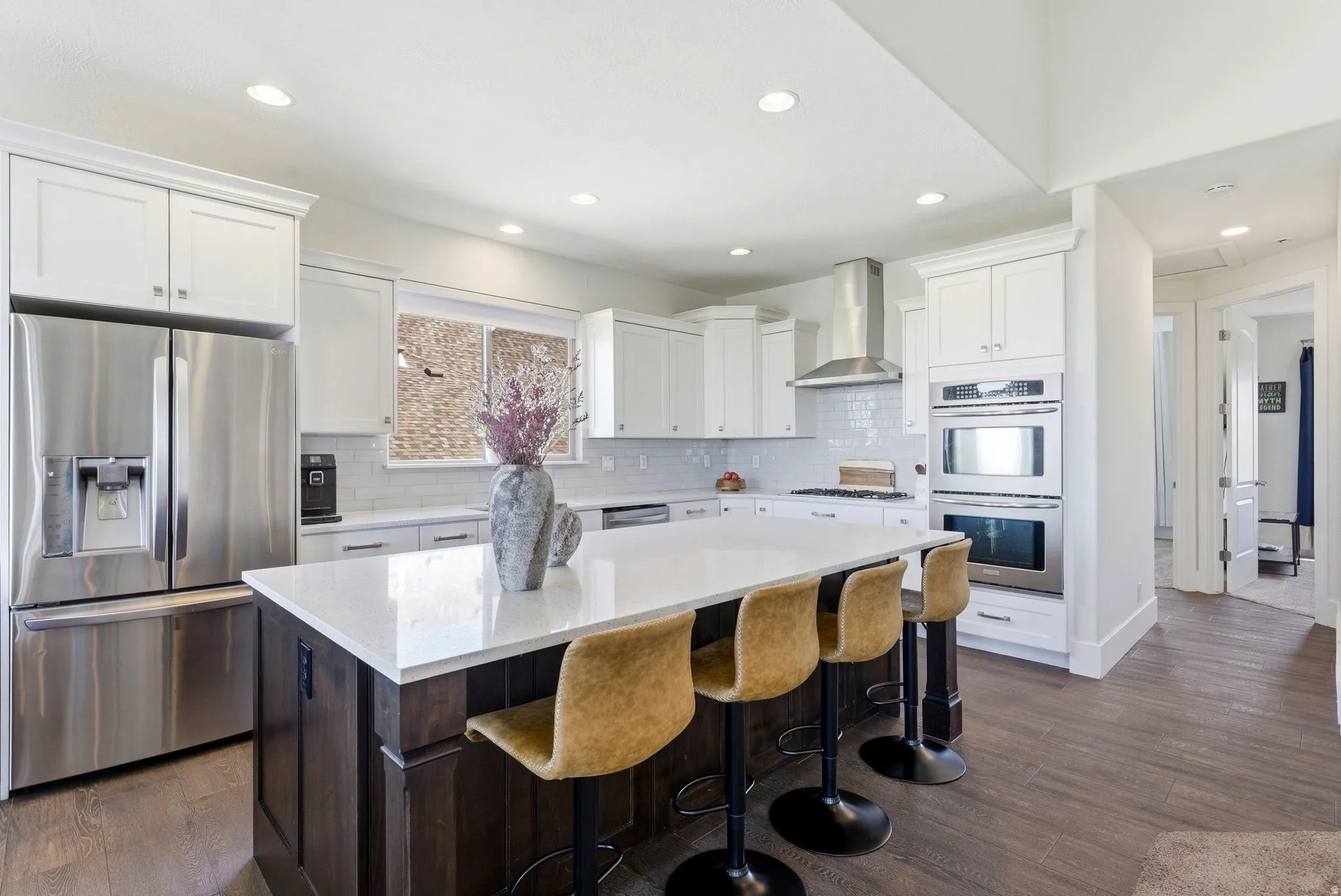 Kitchen featuring stainless steel appliances, dark wood-type flooring, a kitchen island, dual tone cabinetry, and a kitchen bar