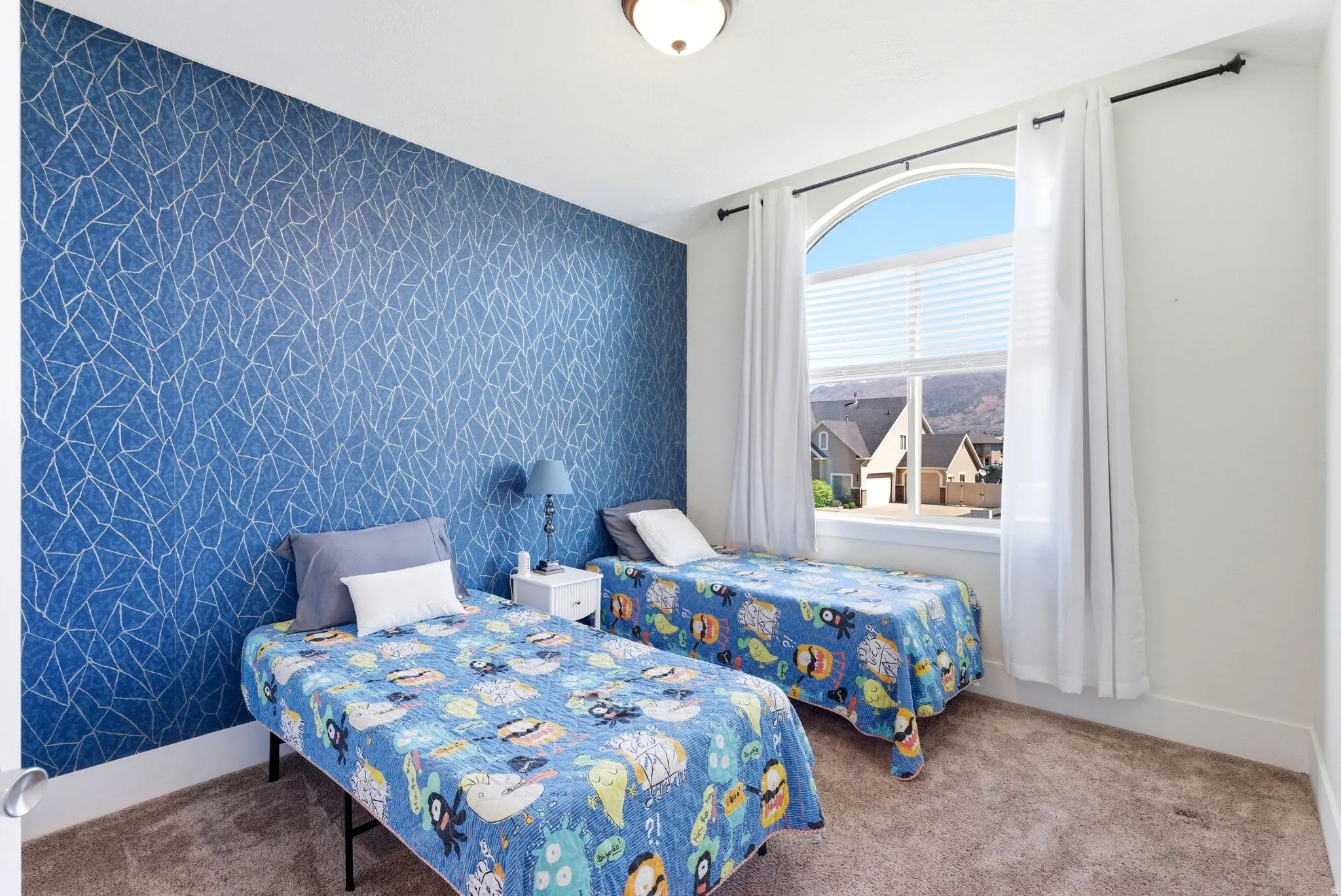 Carpeted bedroom featuring an accent wall and wallpapered walls