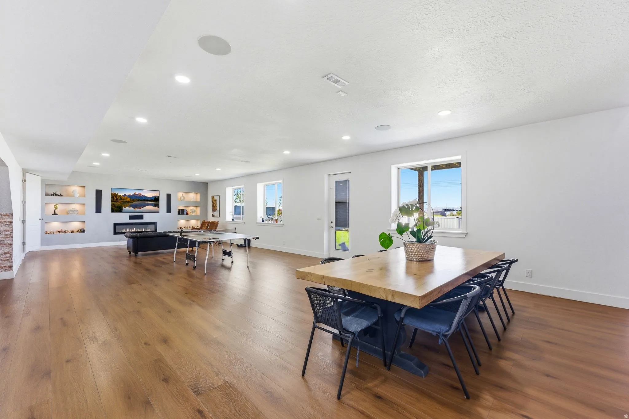 Dining room featuring dark wood-type flooring, healthy amount of natural light, a glass covered fireplace, and recessed lighting