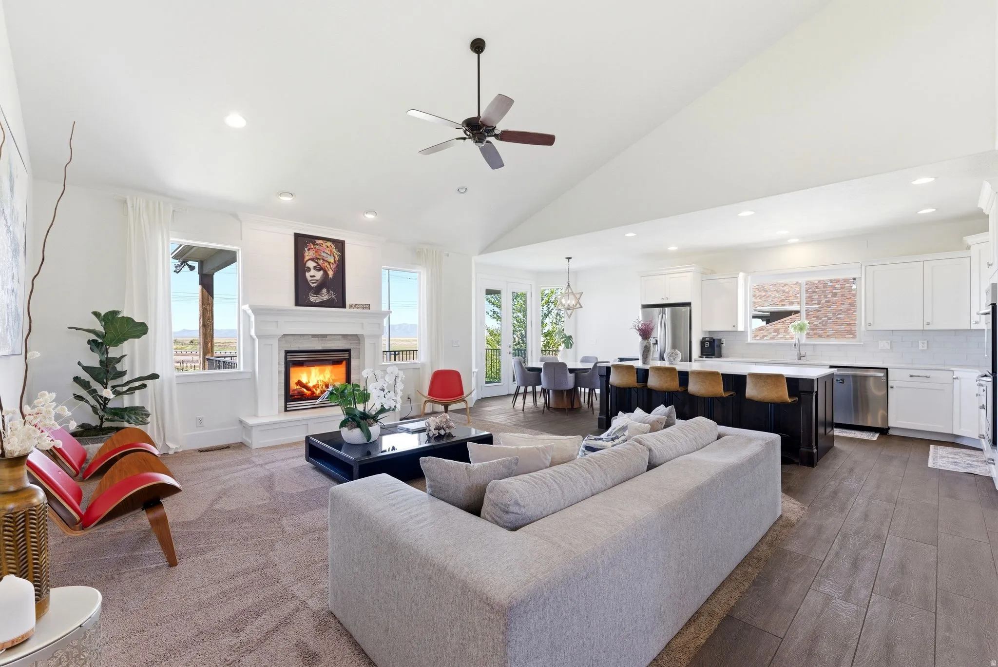 Living area featuring ceiling fan, lofted ceiling, a warm lit fireplace, dark wood-type flooring, and recessed lighting