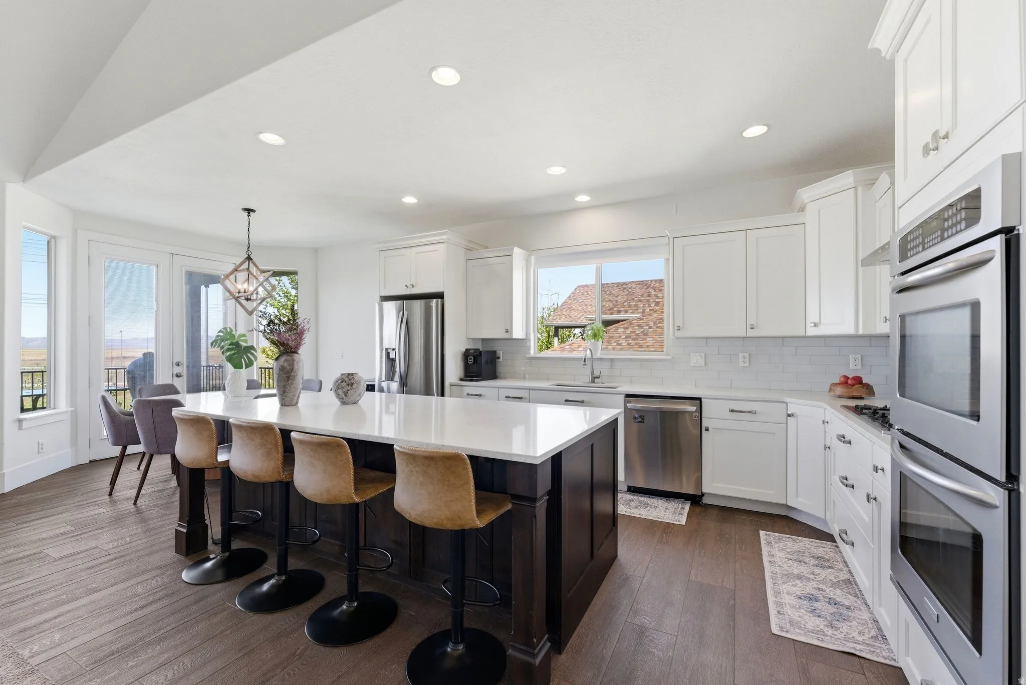 Kitchen with dark wood-style flooring, stainless steel appliances, a kitchen island, two tone cabinetry, and a breakfast bar