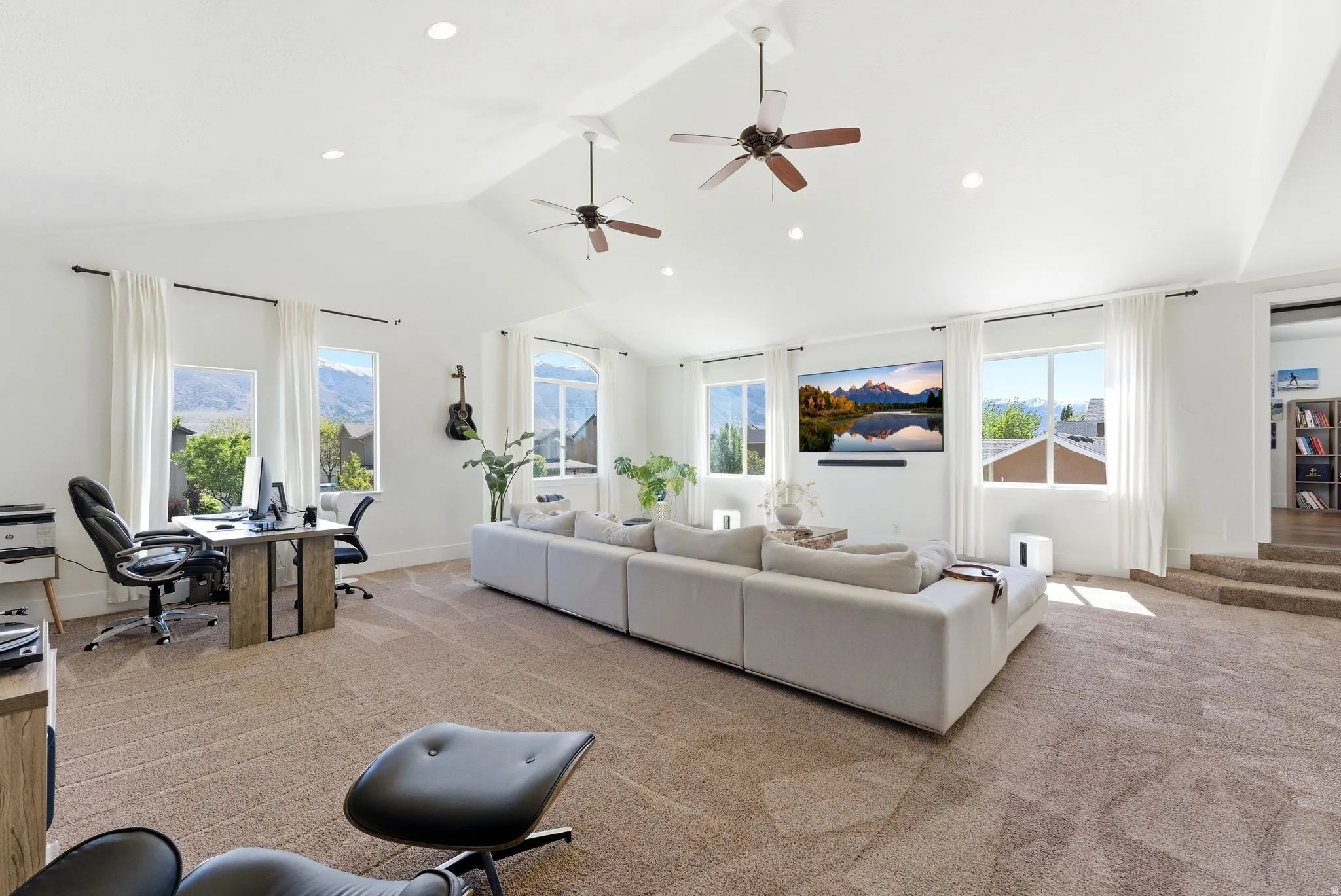 Living room with a desk, light carpet, a high ceiling, ceiling fan, and recessed lighting