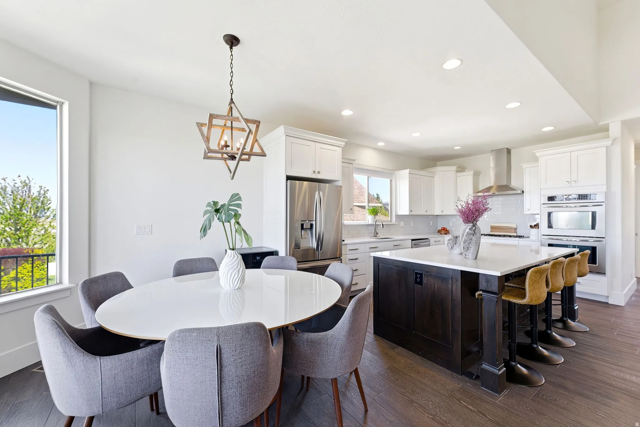Dual tone kitchen featuring two tone color scheme, dark wood finished floors, stainless steel appliances, a kitchen island, and hanging lights