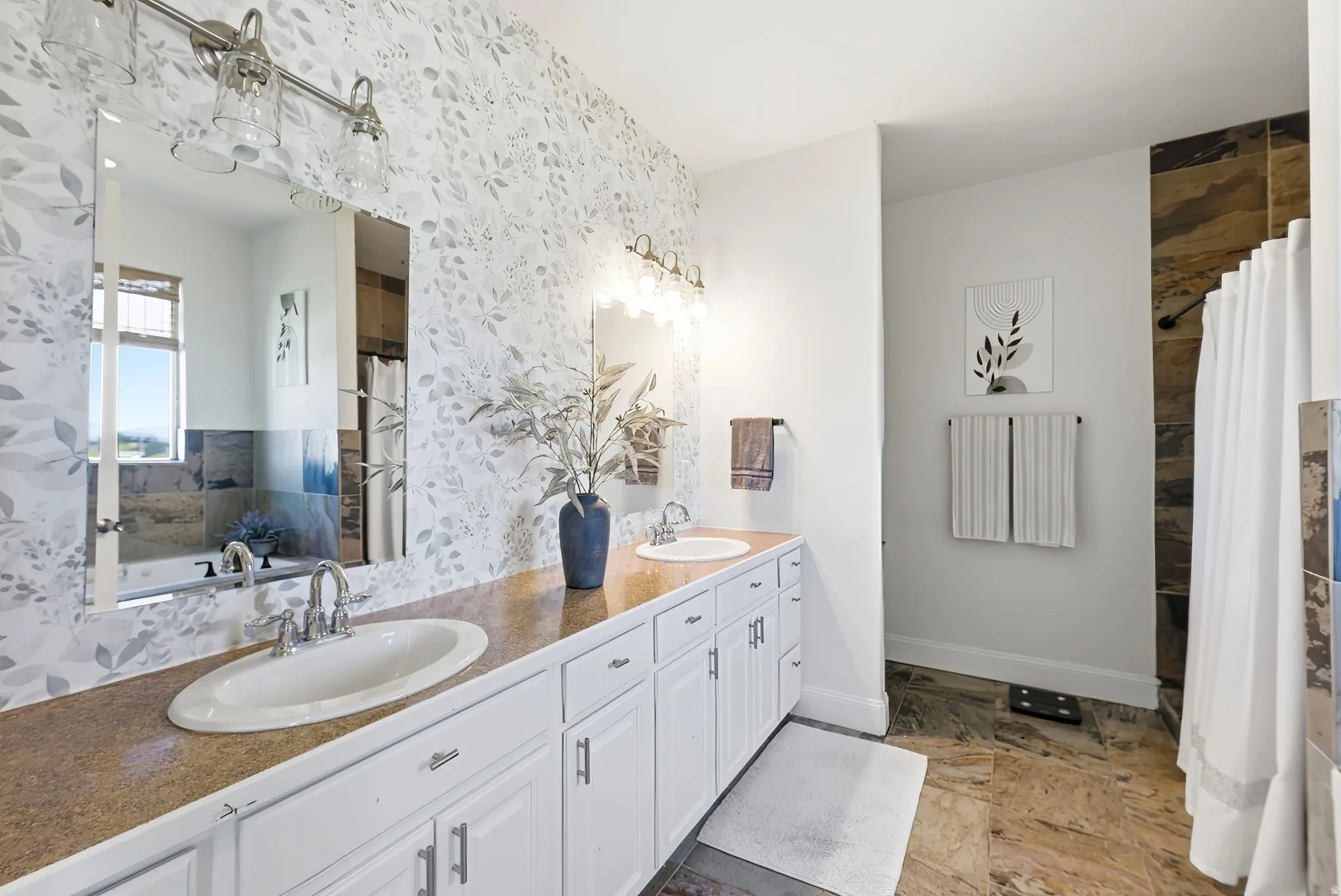 Bathroom with double vanity, dark stone finish flooring, a bath, and a shower with curtain