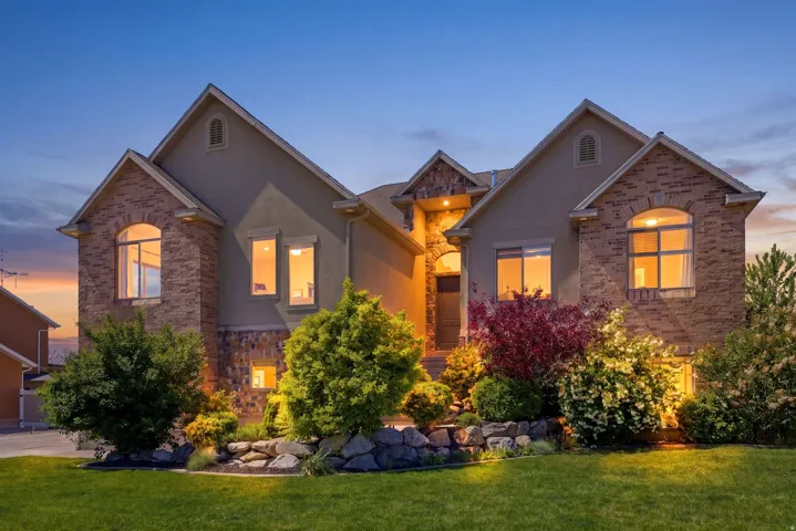 Traditional-style home with stucco siding, a front yard, and stone siding