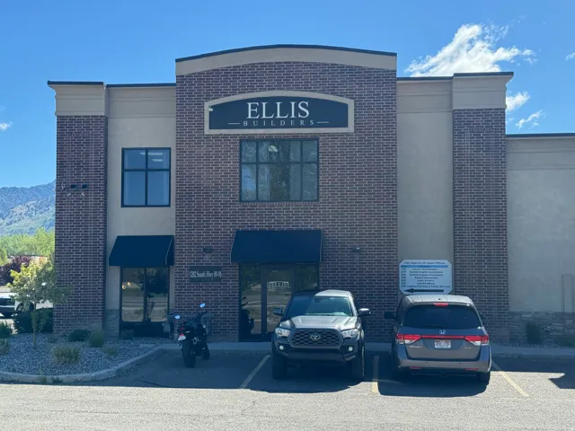 Brick and stucco facade building featuring multiple large windows, dark awnings, and an arched entryway