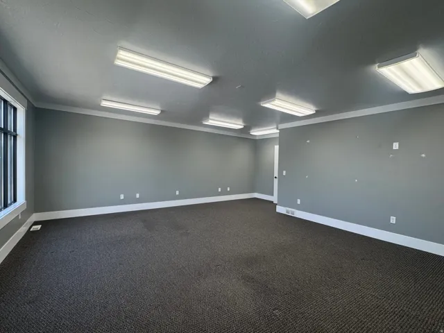 Spacious room featuring neutral grey walls and dark carpeting