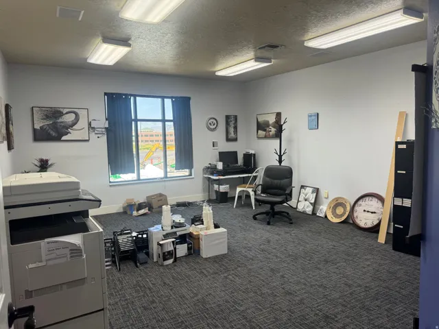 Spacious room with grey textured carpeting, light grey walls, and a large window offering natural light