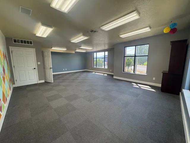 Spacious room featuring checkered carpet flooring and multiple windows
