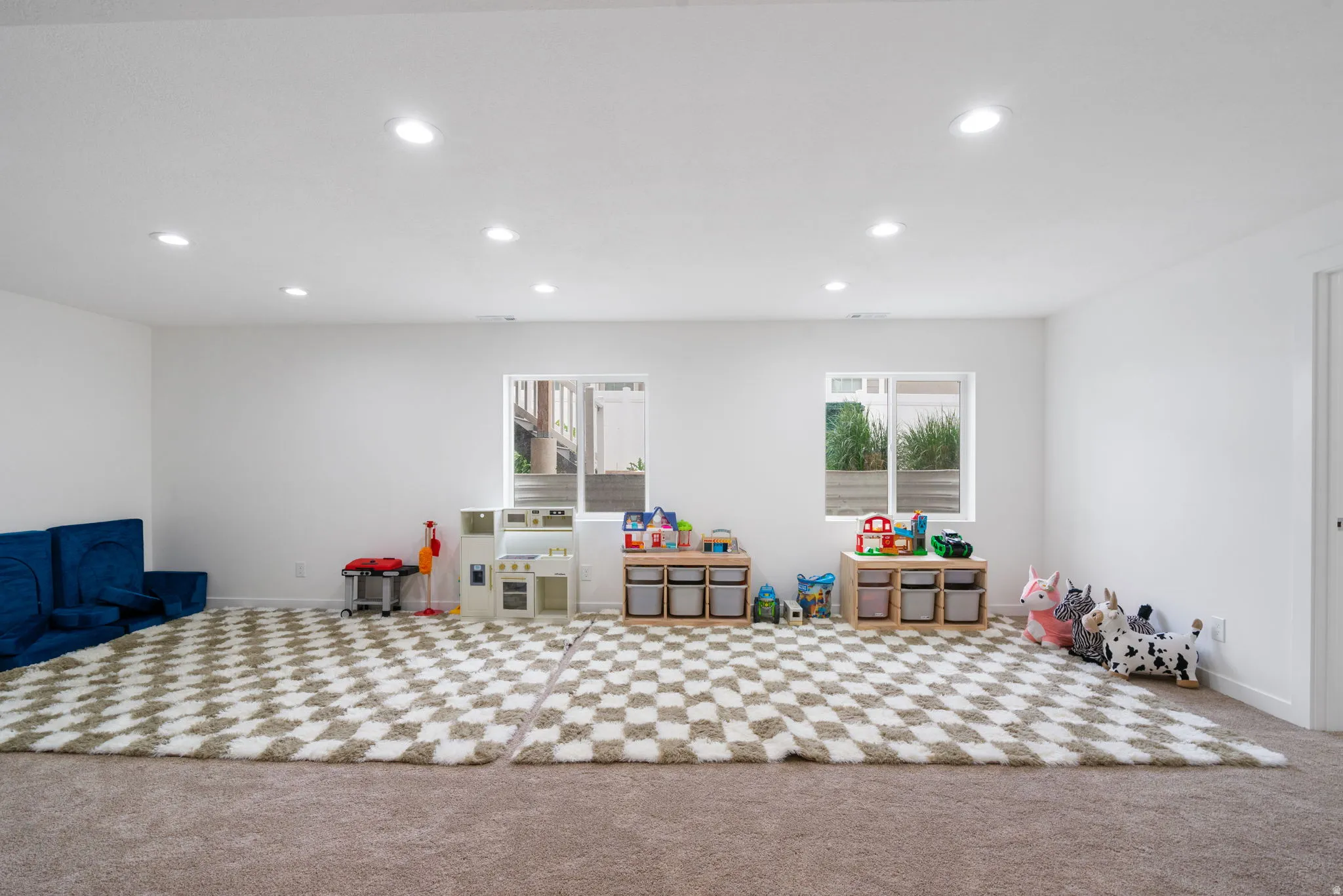 Spacious room featuring neutral carpeting, recessed lighting, and two windows providing natural light
