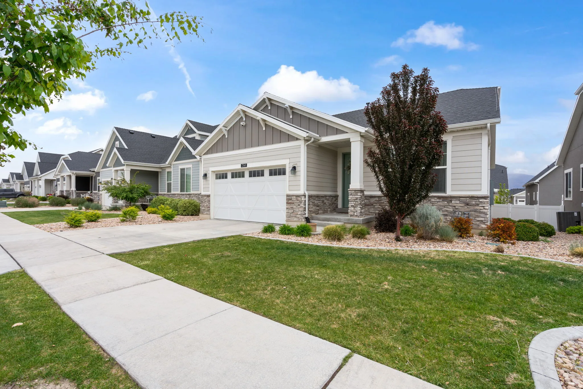 Contemporary single-story residence featuring light gray siding and stone veneer accents