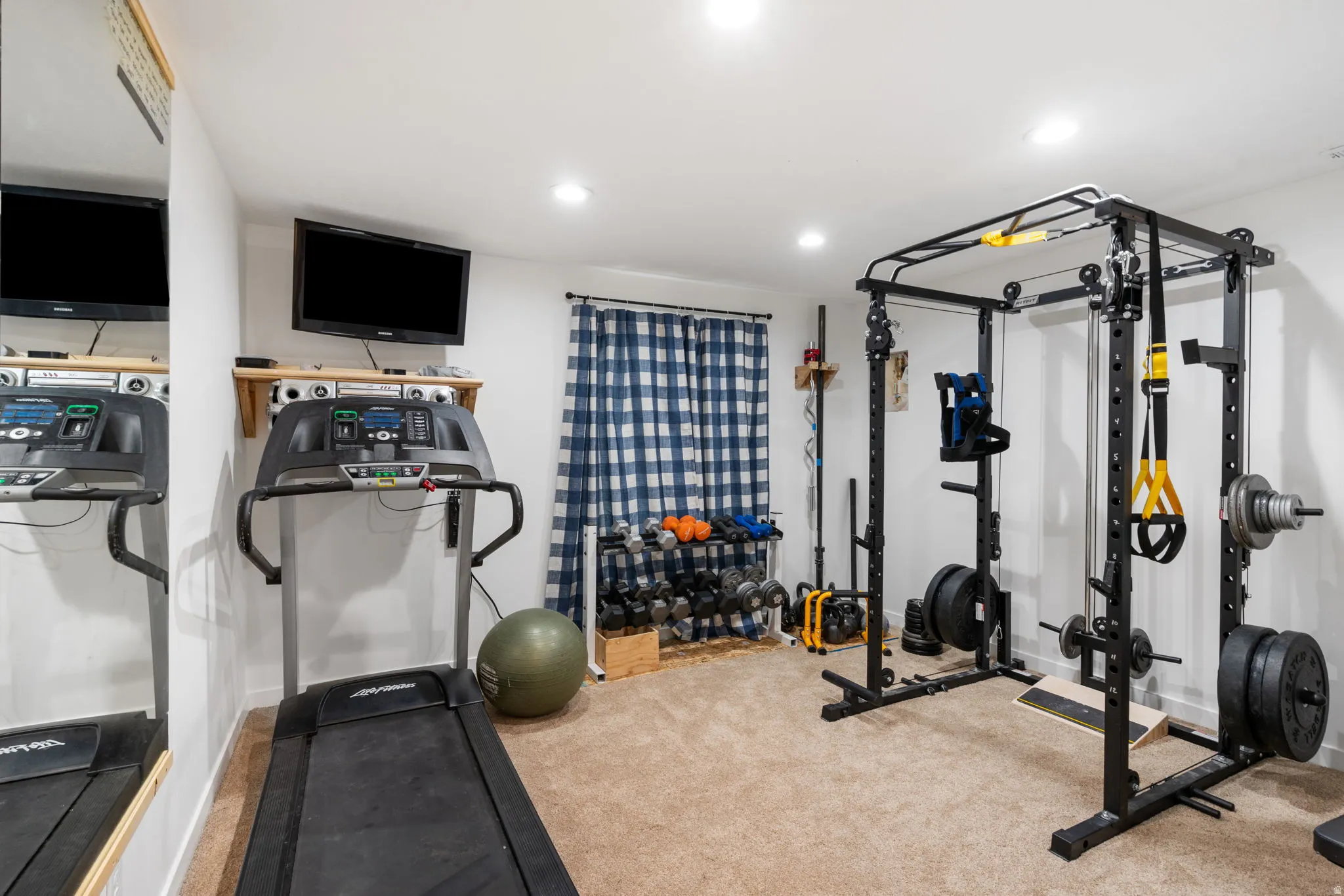 Dedicated fitness space featuring neutral carpeting, recessed lighting, and a wall-mounted television