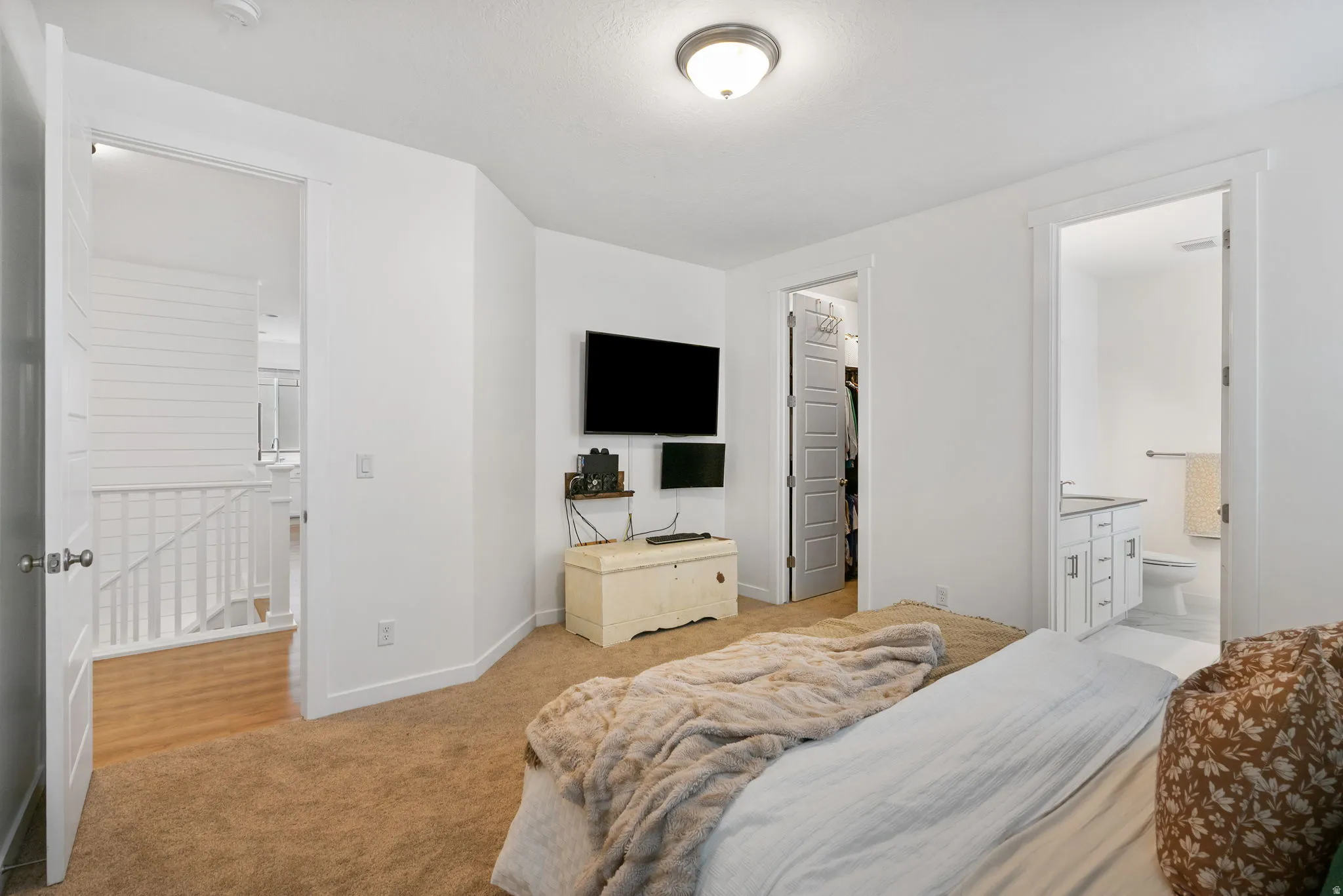 Carpeted room featuring a ceiling-mounted light fixture, white interior doors, and a partial view of a bathroom vanity with a white countertop and base cabinetry