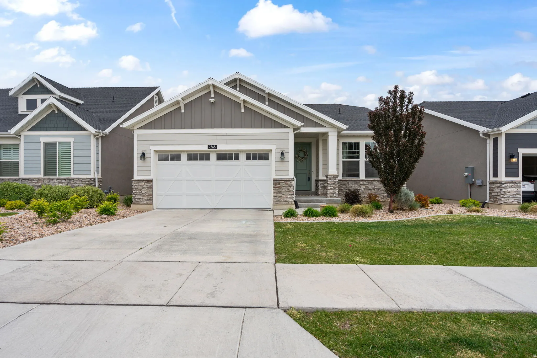 Contemporary ranch-style residence featuring a two-car garage, partial stone facade, and a covered entryway
