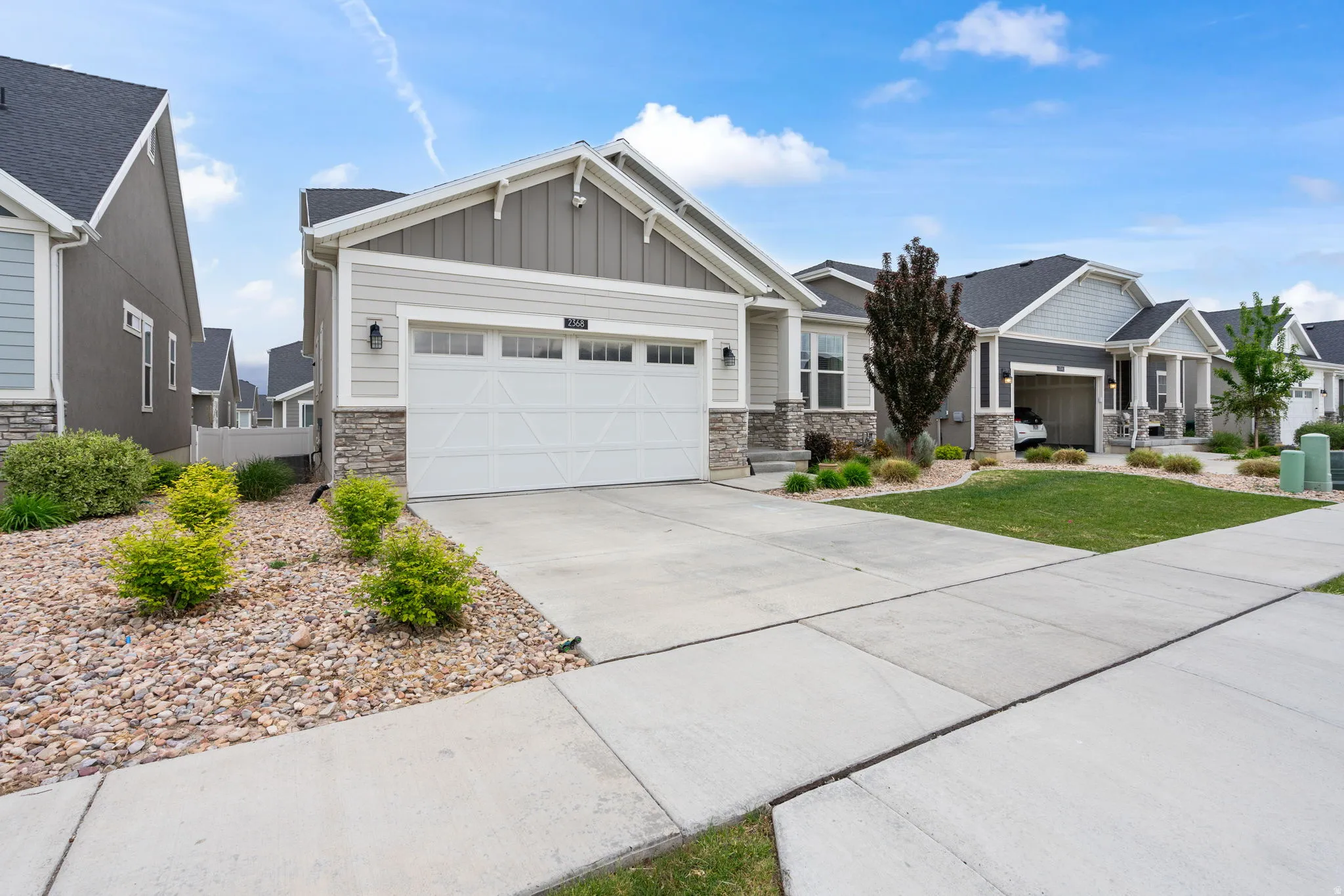 Contemporary home featuring light gray siding with dark gray vertical accents and stone veneer details