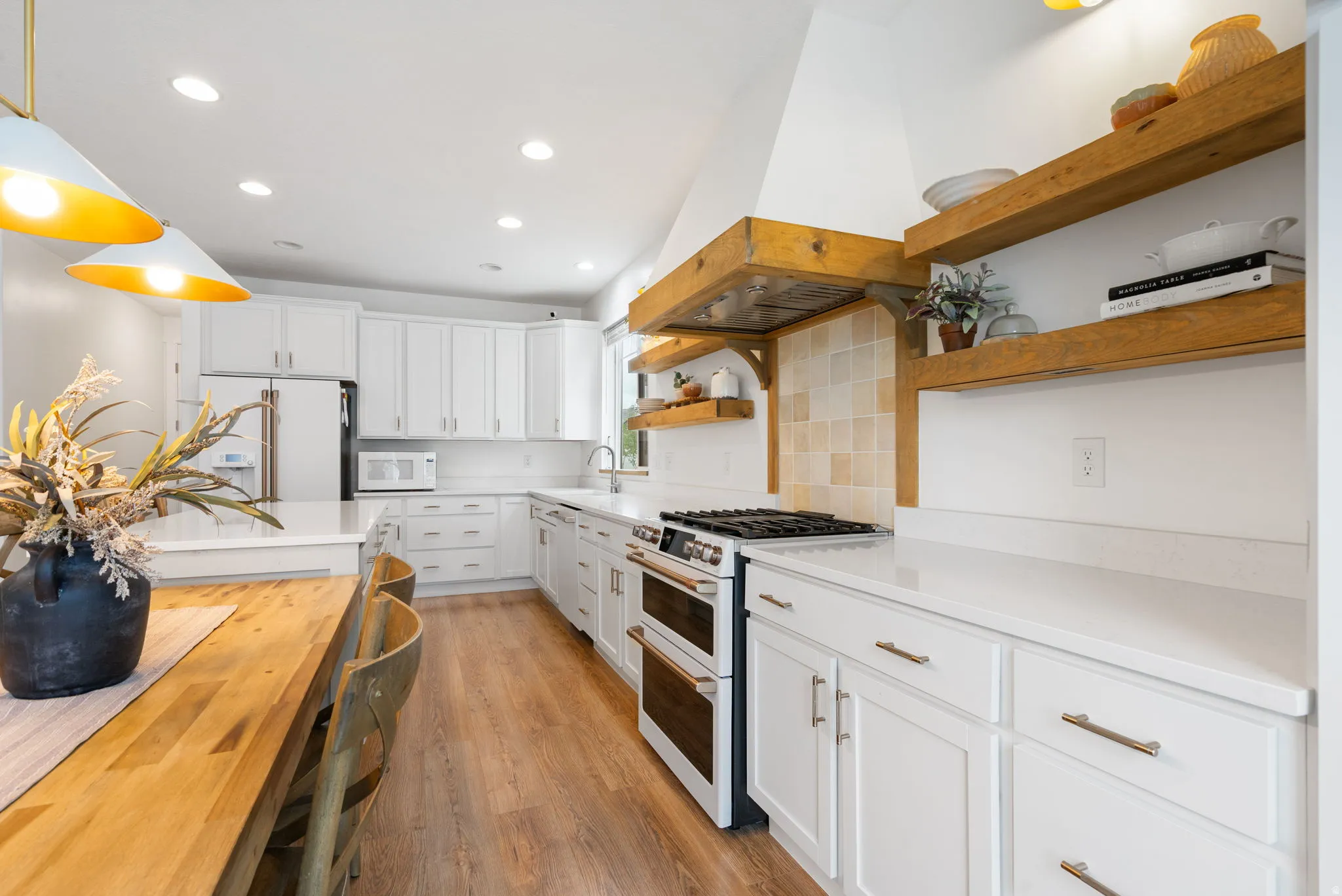 Kitchen featuring white cabinetry, light-toned countertops, wood-finish flooring, recessed lighting, and a double oven range with a custom wood hood