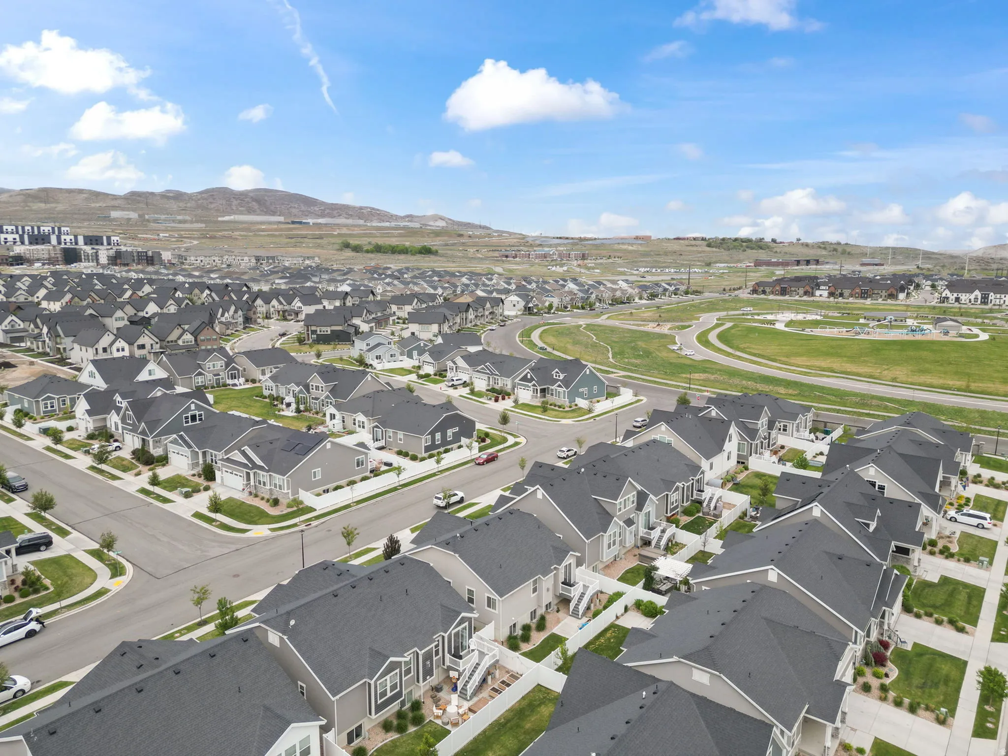 Expansive residential development featuring numerous single-family homes with dark gray roofs and various exterior finishes