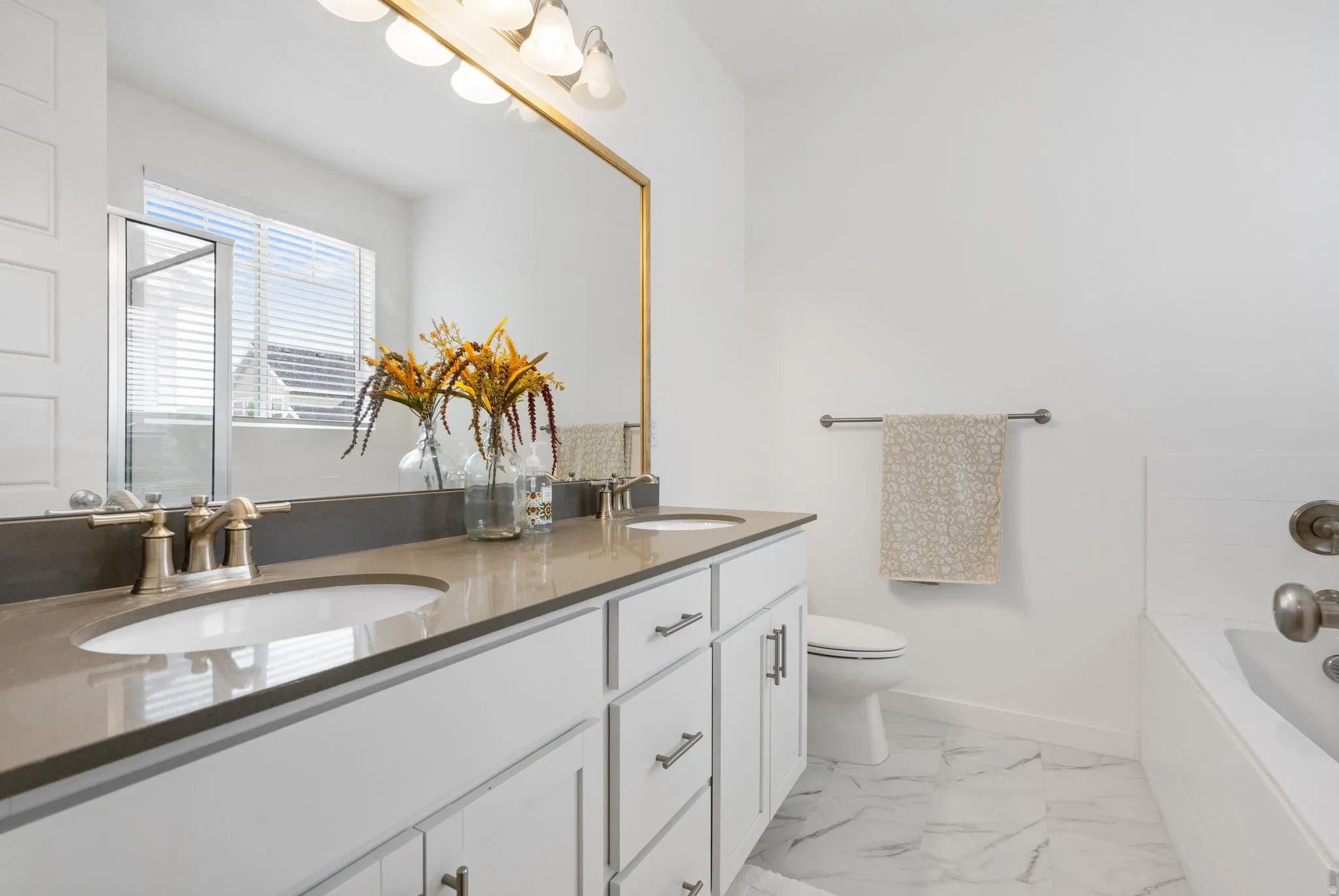 Bathroom featuring a double vanity with light-colored countertops, white cabinetry with brushed nickel hardware, and dual undermount sinks